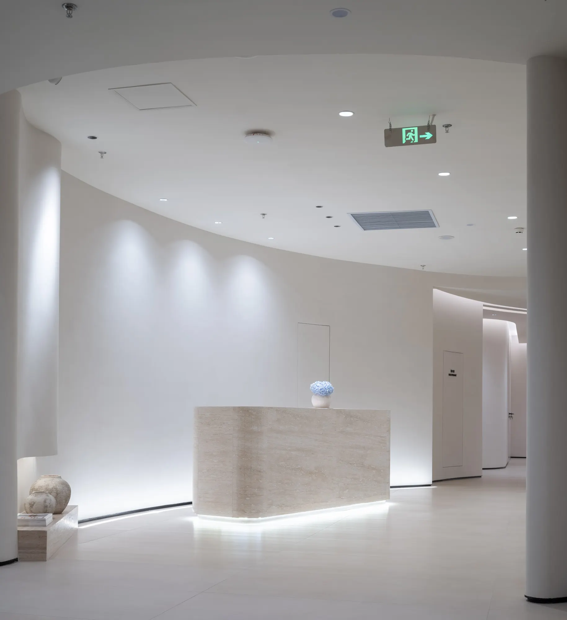 Travertine reception desk under soft cove lighting at the partner clinic